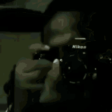 a person holding a nikon camera in their hand