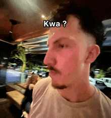 a man with a beard and mustache is wearing a white shirt with kwa written on his forehead