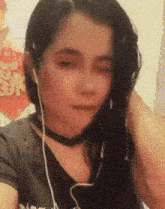 a girl wearing headphones and a choker looks at the camera with her eyes closed