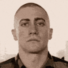 a close up of a man 's face with a shaved head looking at the camera .
