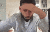 a man with a beard is covering his face with his hand