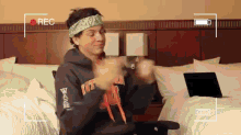 a man wearing a headband that says zips is sitting on a bed with a laptop