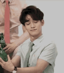 a man in a shirt and tie is holding a green bottle of water .