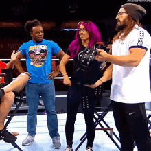 a woman with purple hair is standing next to a man in a blue shirt that says booty on it