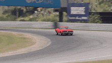 a red car is driving on a race track with a pepsi sign behind it
