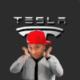 a man wearing a red hat and tie is standing in front of a tesla logo