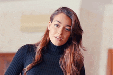 a woman wearing a black turtleneck sweater is standing in a room .
