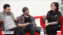 three people sitting on a red couch with bring the noise written on the bottom right