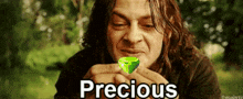 a man is holding a green emerald in his hands and the word precious is above him
