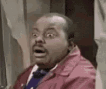 a man wearing a red jacket and tie is making a surprised face .