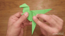 a person is holding a green origami bird that was made in animatica