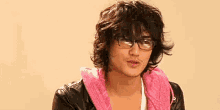 a man wearing glasses and a pink scarf around his neck .