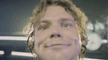 a close up of a man 's face with curly hair making a funny face .