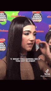 a woman is standing in front of a sign that says kids choice awards on it