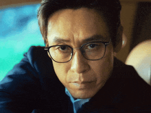 a close up of a man wearing glasses and looking at the camera