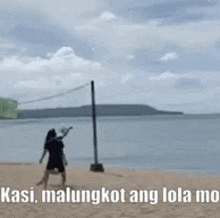 a man is walking on a sandy beach next to a volleyball net .
