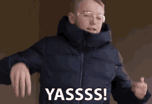 a man wearing glasses and a jacket says yasssss