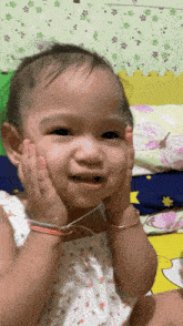 a little girl with a bracelet on her wrist holds her hands to her face
