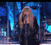 a woman singing into a microphone in front of a drum set