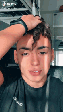 a young man with curly hair is wearing a black t-shirt that says ' alicia santii ' on it
