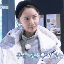 a girl wearing a headband and a white jacket has korean writing on her jacket