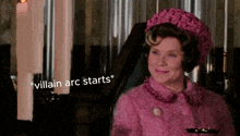a woman in a pink coat and hat is smiling with the words " villain arc starts " above her