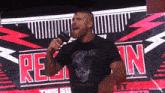a man is speaking into a microphone in front of a sign that says " this show "
