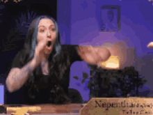a woman with blue hair is sitting at a table with a sign that says neperthians
