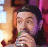 a man with a beard is drinking from a can of soda .