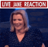 a woman is smiling in front of a sign that says " live jane reaction "