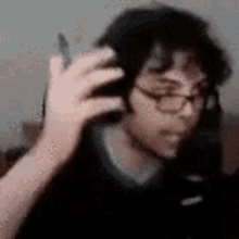 a blurry picture of a man wearing glasses and headphones holding a cell phone .