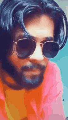 a man with a beard is wearing sunglasses and an orange shirt .