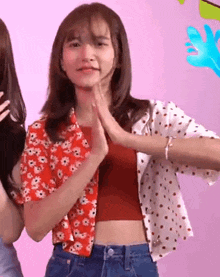 a girl wearing a red crop top and polka dot shirt is clapping