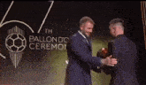 a man in a suit is shaking hands with another man in a suit at the ballon d ' ceremo