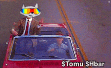 a man in a suit and tie is driving a red car with a cat on his head and the words $tomu $hbar below it