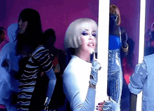 a woman in a white wig and gloves stands in front of a mirror
