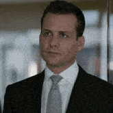 a man in a suit and tie looks to his left