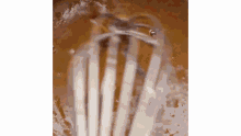 a whisk is being used to mix a liquid in a bowl .