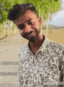 a man in a paisley shirt is smiling and looking at the camera