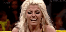 a woman with blonde hair is making a funny face while sitting in a boxing ring .