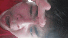 a close up of a person 's face with their hand on their face .