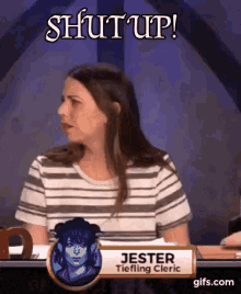 a woman is sitting at a table with a sign that says jester tiefling cleric on it .