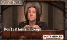a man is sitting at a table with a sign that says critical role .