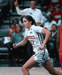 a female basketball player wearing a mystics jersey is running on the court