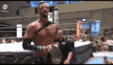 a shirtless wrestler is standing in a wrestling ring
