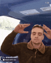 a man in a brown jacket is making a funny face in front of a screen that says " gravelcrew "
