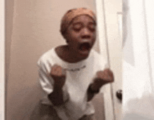 a woman is standing in front of a door with her mouth open and her hands in the air .