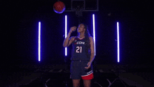 a woman in a coni jersey is holding a basketball and pointing .