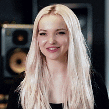 a close up of a woman with long blonde hair wearing a black shirt and smiling .