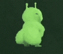 a green cartoon character is dancing in the dark .